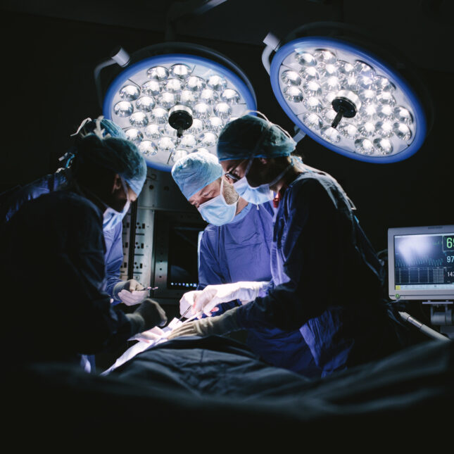 A team of four surgeons doing surgery in a dark operating room — first opinion coverage from STAT