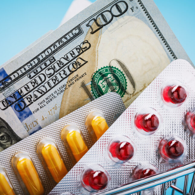 One hundred dollar bill and pills seen in a grocery shopping cart. -- health policy coverage from STAT