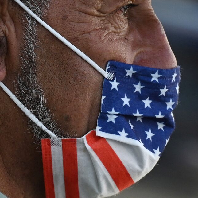 A close up of an older man wearing and american flag printed face bask during the Covid pandemic