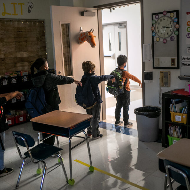 Four kindergarten students line up in a classroom facing the exit, extending their arms for social distance — first opinion coverage from STAT