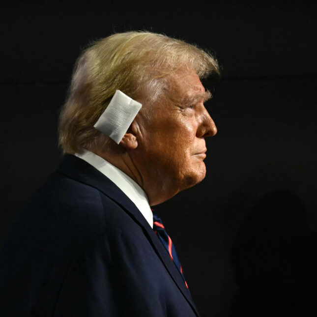 Profile of Donald Trump with a bandaged ear against a black background. -- health